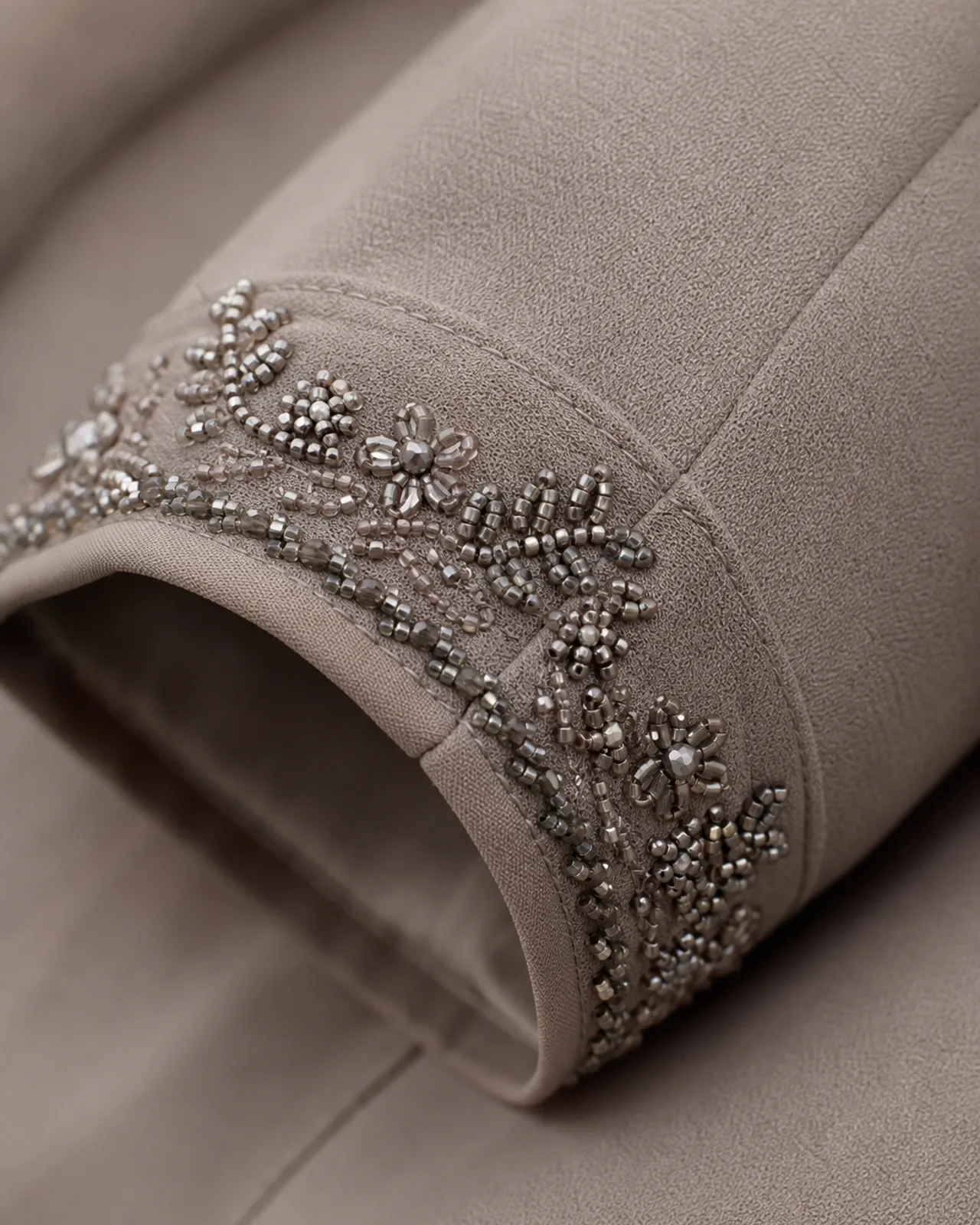 Cuff close-up showing beadwork around the cuff edge, with the sleeve seam and cuff finishing visible