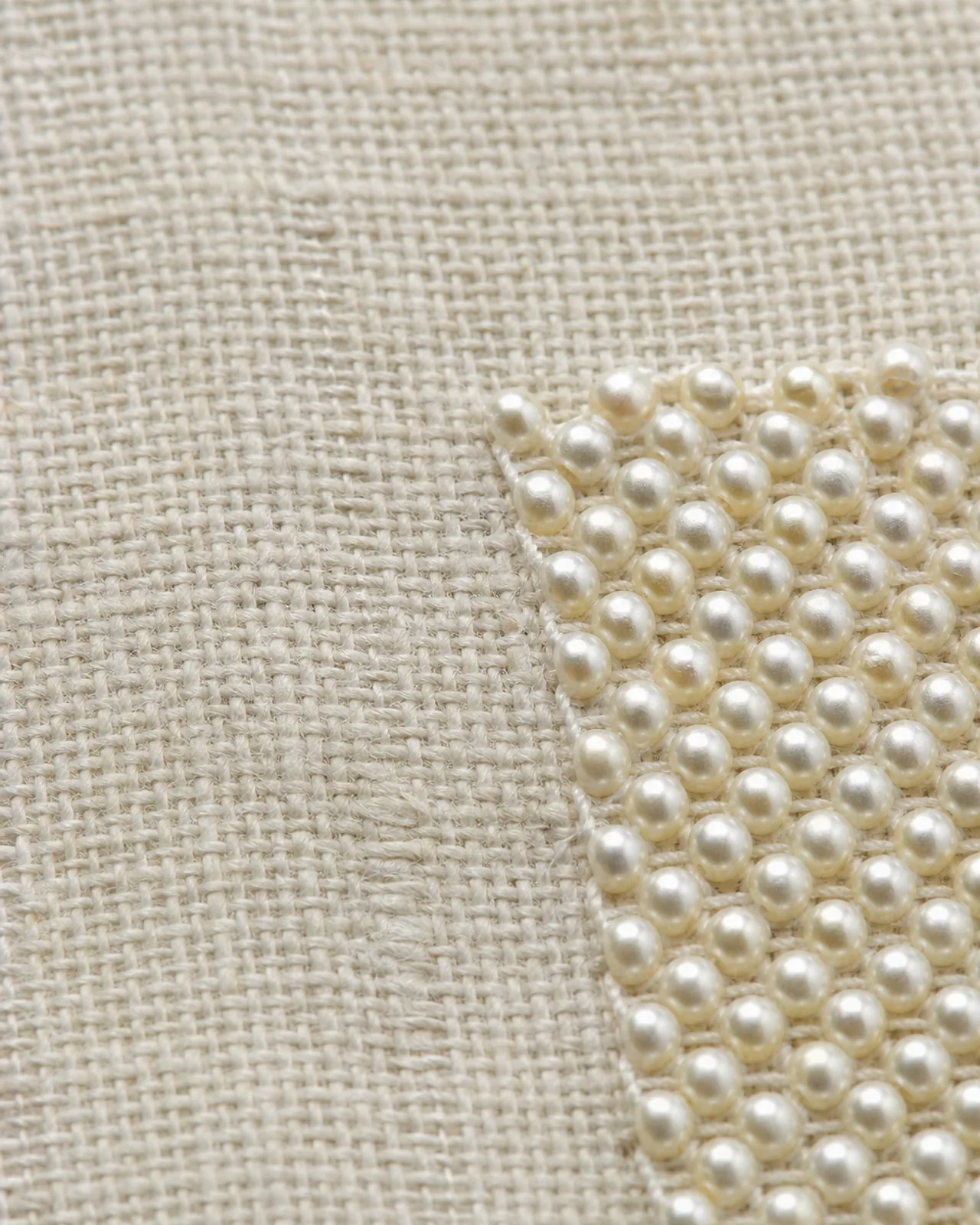 Fabric close-up at roughly three times magnification showing the ground cloth and the weight of the beaded area