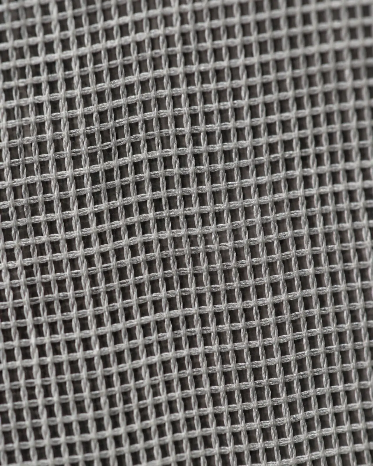 Chiffon close-up at roughly three times magnification, held over a dark layer to show how transparent the fabric is