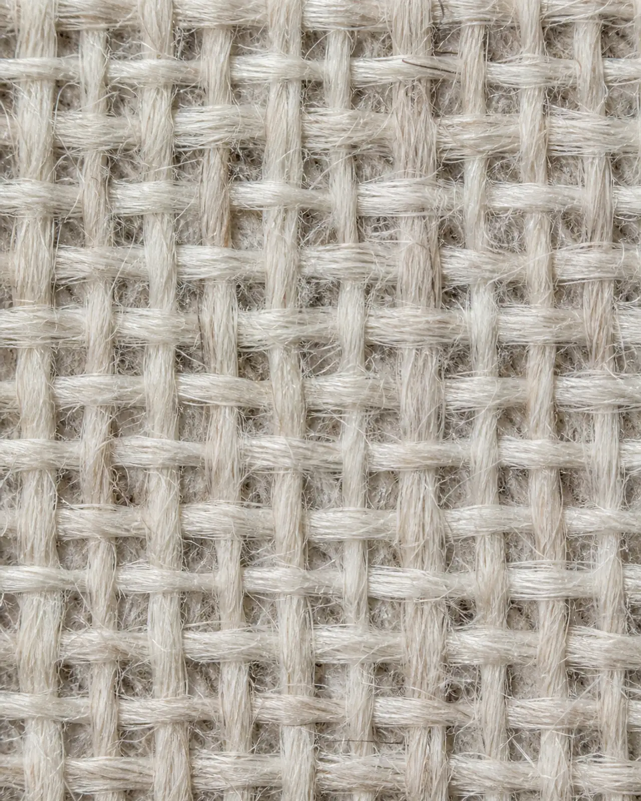 Fabric close-up at roughly three times magnification showing the ground fabric under the embroidery, with the backing from the inside