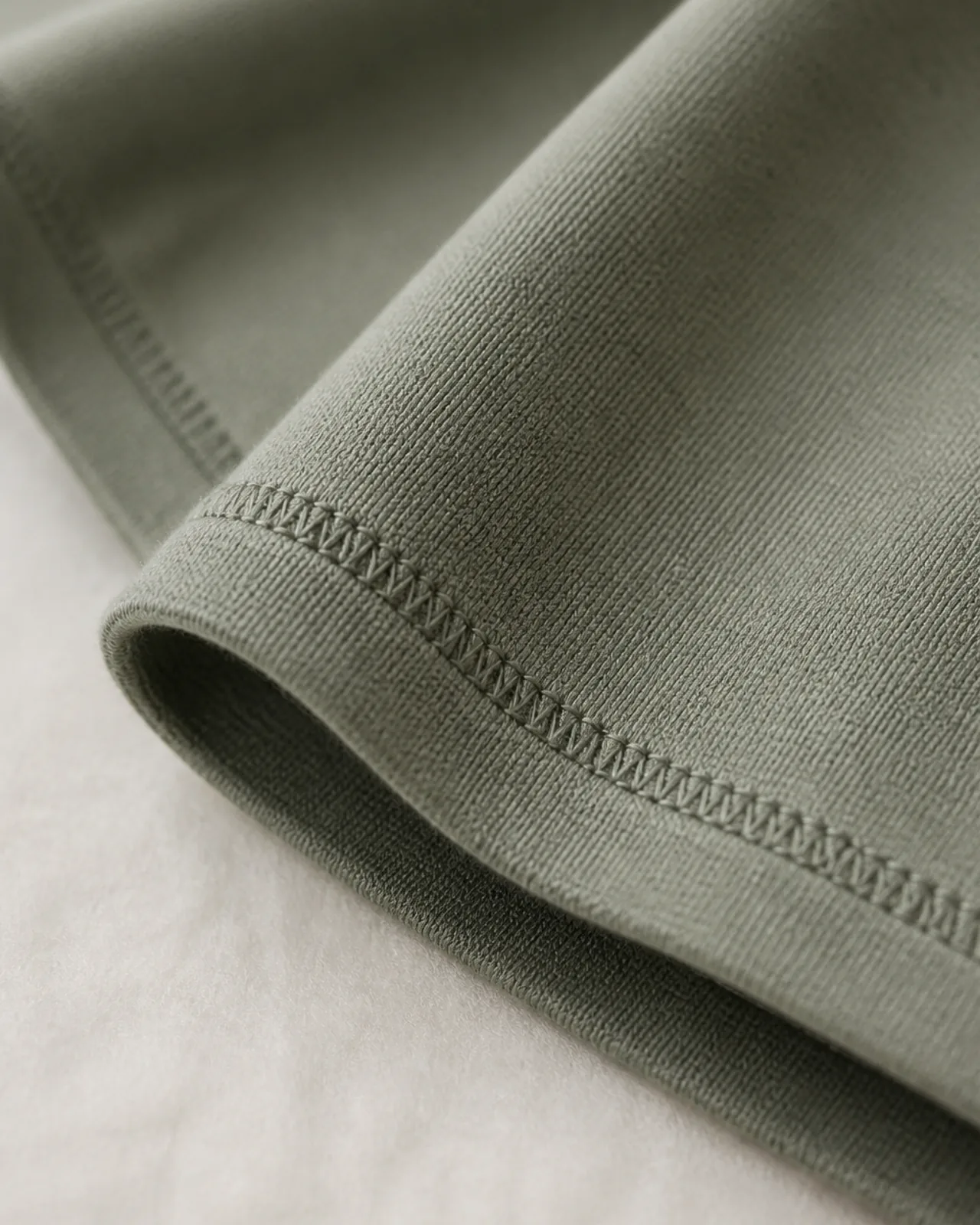 Edge finishing close-up showing the hem stitch on a knit, including how the edge sits flat rather than curling