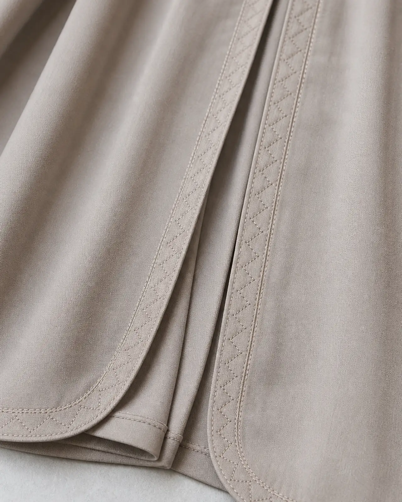 Front opening and split hem detail, showing the topstitched edge and where an embroidered border would sit
