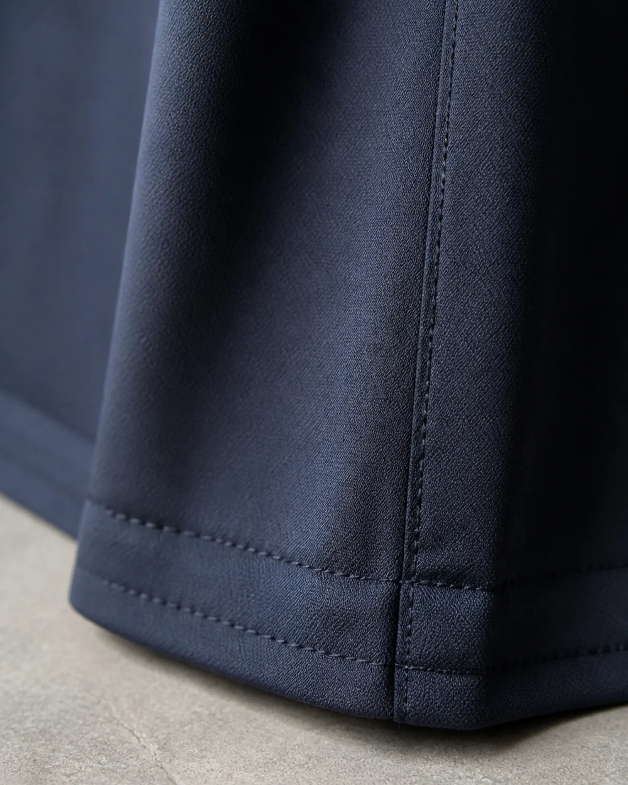 Edge finishing close-up at the hem, showing the stitched edge, corner treatment and stitch density
