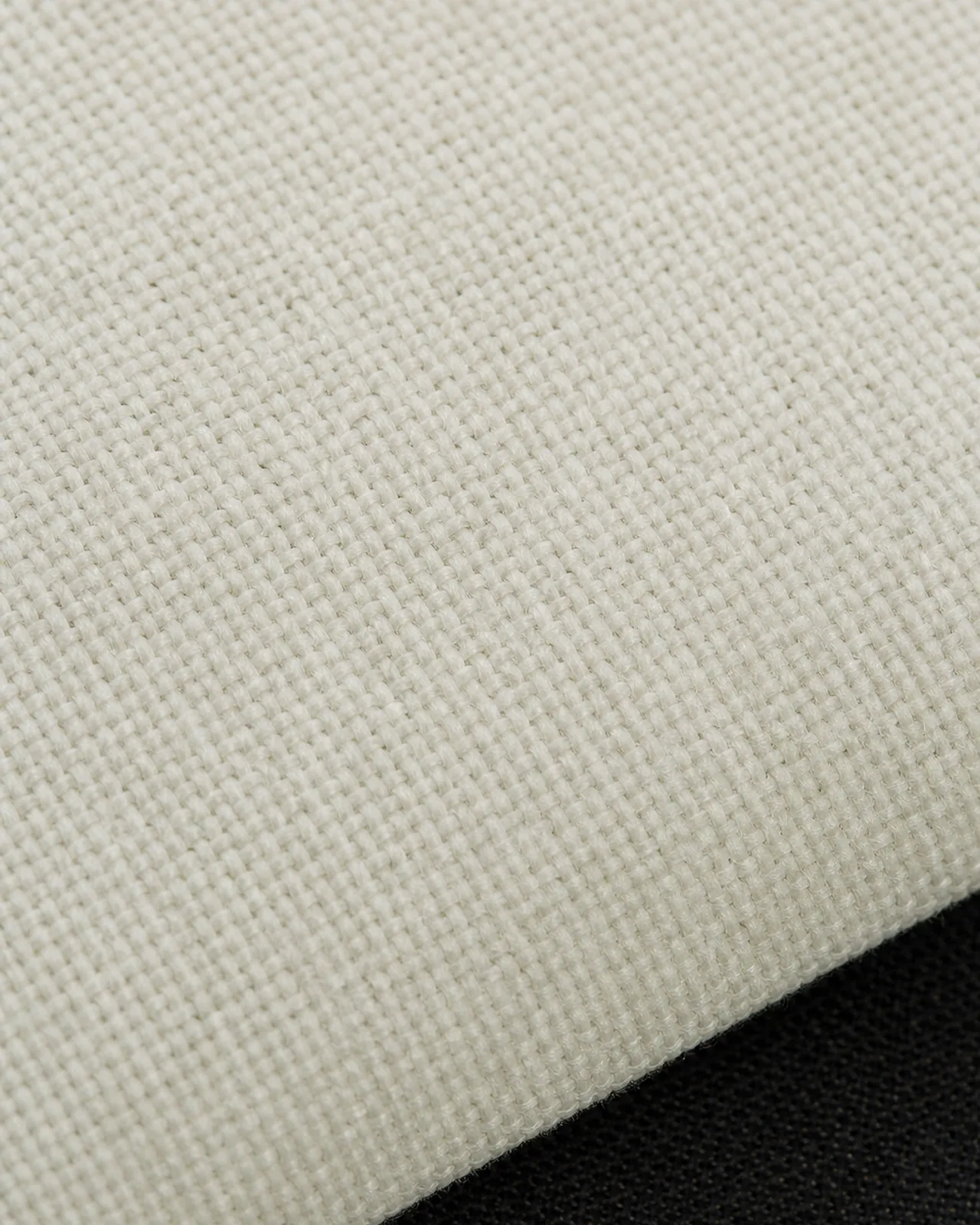 Nida fabric close-up at roughly three times magnification, matte surface, held over a dark inner layer to show opacity
