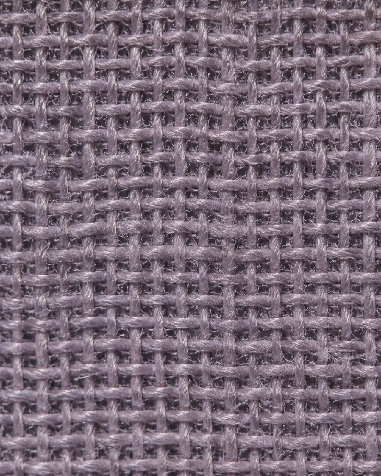 Fabric close-up at roughly three times magnification, held over a dark layer to show opacity of the prayer garment fabric