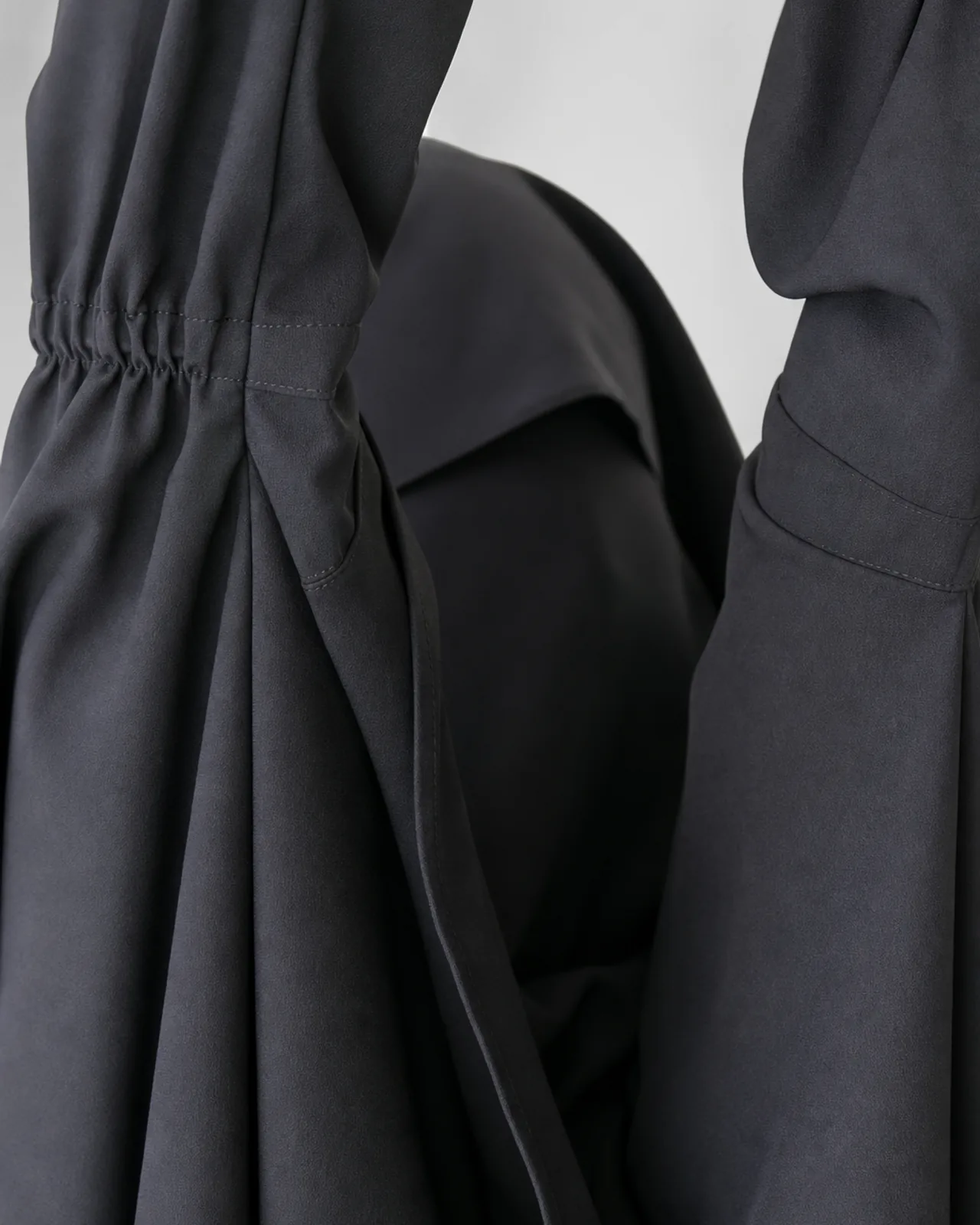 Detail of the sleeve opening and head covering section, showing coverage when the arms are raised